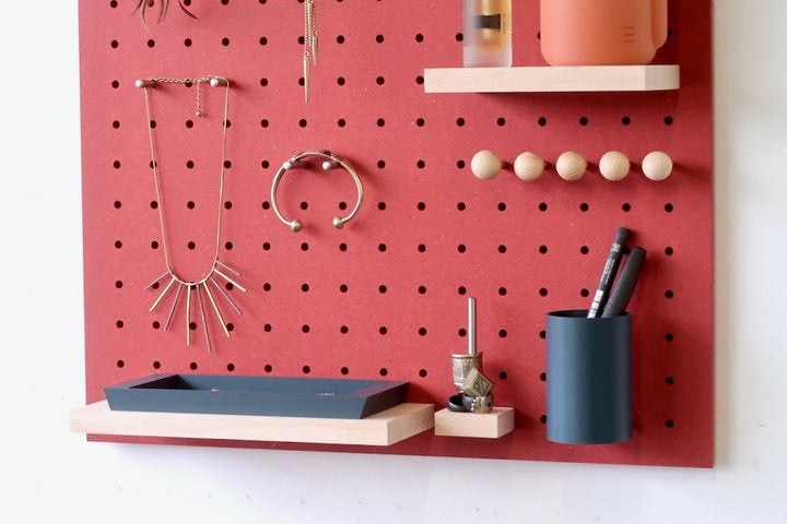 close up of red pegboard system showing stationary pot and a wooden shelf