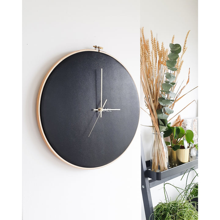 small black lineal wall clock next to houseplant